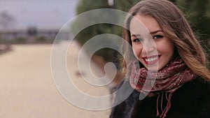 Close-up portrait of a beautiful girl in black coat walking in park.