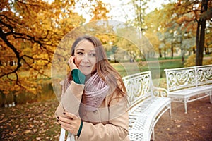 Close up portrait of a Beautiful girl in dark dress and black hat standing near colorful autumn leaves. Art work of romantic woman