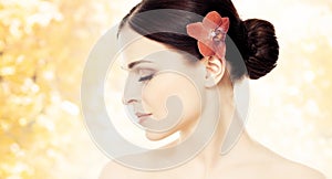 Close-up portrait of a beautiful girl with an orchid flower in h