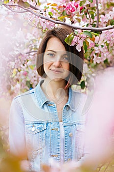 Close up portrait of a beautiful girl with pink hair standing in a blooming apple garden. Spring, outdoors.