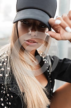 Close-up portrait of a beautiful glamour caucasian young woman in a fashionable black cap with a stylish black denim jacket posing