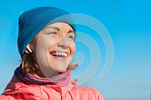 Close up portrait of beautiful laughing woman listening to music in earphones