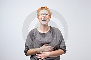 Close up portrait of a beautiful mid adult woman with red hair laughing standing on gray background.