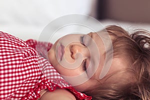 Close up portrait of a beautiful nine month old baby girl sleeping on blurred background. Sleeping child face. Cute