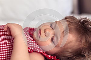 Close up portrait of a beautiful nine month old baby girl sleeping on blurred background. Sleeping child face. Cute