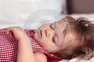 Close up portrait of a beautiful nine month old baby girl sleeping on blurred background. Sleeping child face. Cute