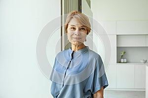 Close up portrait of beautiful older woman smiling and standing by wall