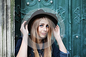 Close up portrait of beautiful playful smiling girl wearing stylish wide-brimmed black hat. Model looking at camera