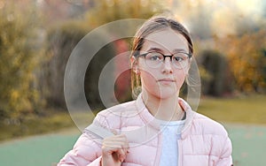 Close-up portrait of beautiful preteen girl in fashion glasses with serious face expression outside in autumn park