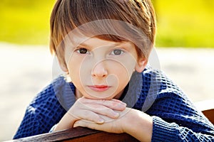 Close-up portrait of a beautiful red-haired boy with a very serious look. A sad expression on his face. Outdoor, copy space