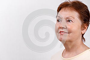 Close-up portrait of a beautiful senior woman looking to the side on a white background in a light T-shirt. isolated