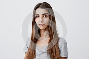 Close up portrait of beautiful serious dark-haired caucasian woman with long hairstyle in casual gray shirt looking in