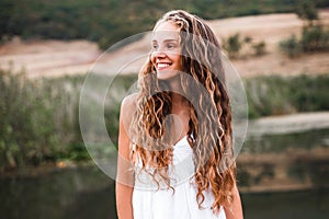 Close-up portrait of a beautiful smiling blonde girl with natural curls.