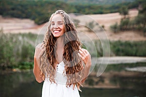 Close-up portrait of a beautiful smiling blonde girl with natural curls.