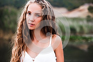 Close-up portrait of a beautiful smiling blonde girl with natural curls.