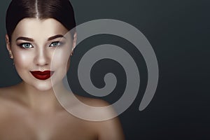 Close up portrait of beautiful smiling dark-haired model with perfect make up and centre part sleek bun