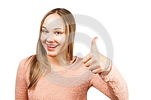 Close up portrait of beautiful smiling young woman in a beige shirt looking and showing thumb up, isolated on a white background