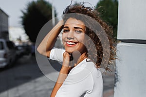 Close-up portrait of beautiful smiling young woman with long brunette hair flying on the wind