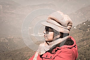 Close-up Portrait of a beautiful stylish asian woman in winter clothes, stands sideways on a background snow mountain. An