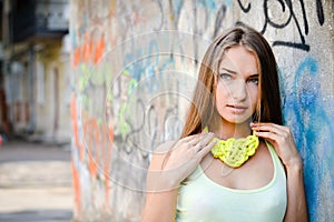 Close up portrait of beautiful stylish fashion girl having fun gently smiling and looking at camera on graffiti city wall