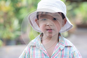 close up portrait of beautiful sweet boy, wearing White bucket hat and colorful shirt, looking at camera, big dark eyes