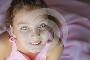 Close up portrait of beautiful teen girl in pink dress enthusiastically with a smile looking at the camera