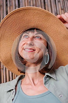 Close-up portrait of a beautiful traveling brunette woman wearing a hat, stylish summer clothes. Cheerful young woman smiling on