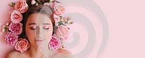Close up portrait of beautiful woman face wih bright make up and perfect skin posing with roses on pink background