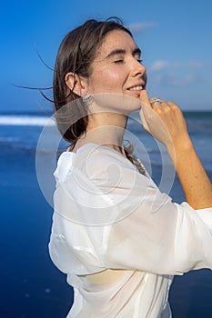 Close up portrait of beautiful woman with jewelry. Closed eyes. Hair and clothes are blown by the wind. Caucasian woman enjoying