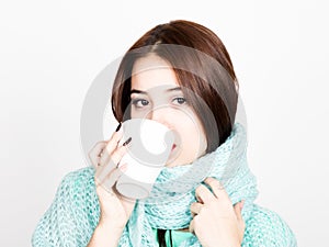 Close-up portrait of beautiful woman in a woolen scarf, drinking hot tea or coffee from white cup