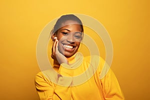 Close up portrait of beautiful young african woman laughing over yellow background