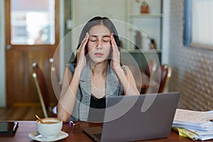 Close-up portrait of beautiful young Asian business woman face is massaging the head with both hands headache from work stress