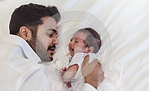 Close up portrait of beautiful young asian or caucasian father looking at healthy crying newborn baby.