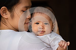 Close-up portrait of beautiful young Asian mother holding baby girl