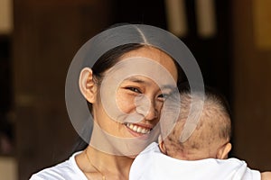 Close-up portrait of beautiful young Asian mother holding baby girl