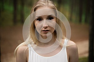 Close up portrait - Beautiful young blonde woman forest nymph in white dress in evergreen wood