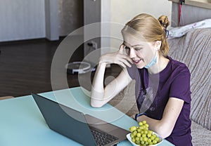 Close up portrait of a beautiful young blondy woman smiling and looking at laptop screen