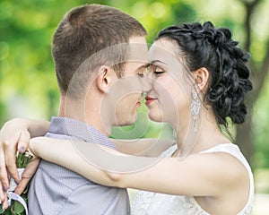 Close-up portrait of beautiful young couple female bride and male bridegroom kissing in summer park. Woman wife hugging man husban