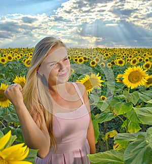 Close up portrait of a beautiful young girl in pink dress in a field of sunflowers