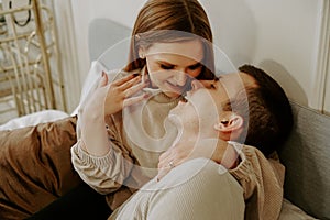 Close-up portrait of a beautiful young kissing couple in bed at home