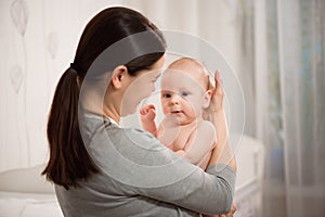 Close up portrait of beautiful young mother girl kissing her newborn baby