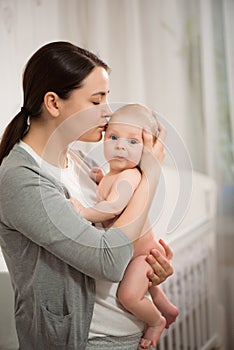 Close up portrait of beautiful young mother girl kissing her newborn baby