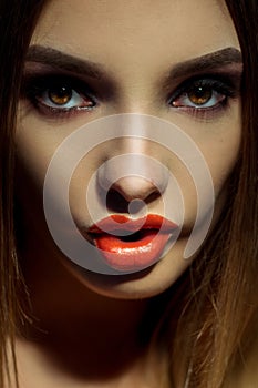 Close up portrait of beautiful young woman with brown eyes and make up bitting a lips and looking at the camera