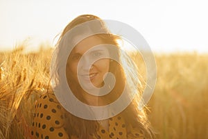 Close-up portrait of beautiful young woman in a countryside field. Female face in the rays of sunset. Freedome and