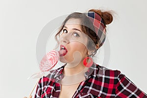Close up portrait of beautiful young woman eating lollipop over white background