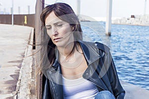 Close up portrait of beautiful young woman leaning to a wall outdoors and looking away thinking