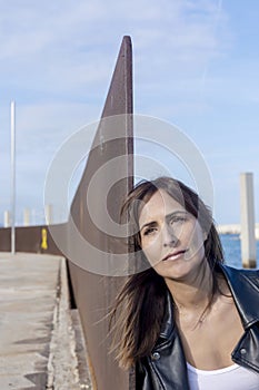 Close up portrait of beautiful young woman leaning to a wall outdoors and looking away thinking