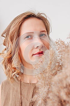 Close up portrait of beautiful young woman in linen dress with dried flowers, eco natural beauty concept