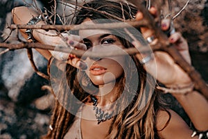 Close up portrait of beautiful young woman looking in camera through dry branches