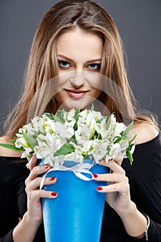 Close-up portrait of beautiful young woman with luxury jewelry and perfect make up holding bouquet